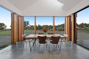a dining room with a table and chairs and windows at Sky Fall in Sea Ranch