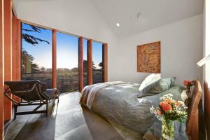 a bedroom with a bed and a chair and windows at Sky Fall in Sea Ranch