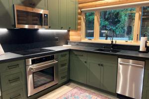 a kitchen with green cabinets and a sink at Cabin Fever in Gualala +21 photos