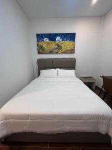 a bedroom with a white bed with a painting on the wall at The Haven Suites Batam in Tanjunguma +1 photo