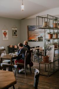 two people sitting at tables in a restaurant at Green Sheep Boutique Hotel in Kazbegi