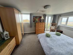 a bedroom with a bed and a dresser and windows at Dream view holiday home in Castletown