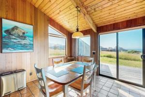 a dining room with a table and chairs and windows at Albatross Reach in Sea Ranch