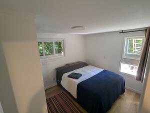 a small bedroom with a bed and two windows at Entire Garden Suite in North Vancouver in North Vancouver