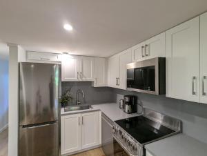 a kitchen with white cabinets and a stainless steel refrigerator at Entire Garden Suite in North Vancouver in North Vancouver