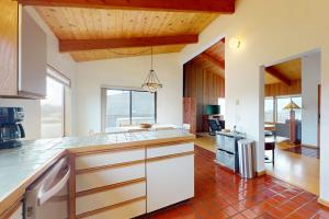 a kitchen with white cabinets and a red tile floor at Whispering Wave in Gualala