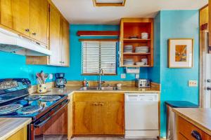 a blue kitchen with a sink and a stove at Clemons' Cottage in Sea Ranch