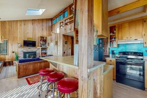 a kitchen with wooden walls and red bar stools at Clemons' Cottage in Sea Ranch