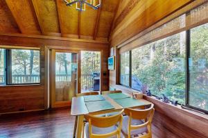 a dining room with a table and chairs and windows at Redwood Grove in Sea Ranch