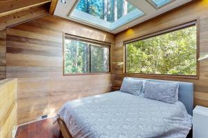 a bedroom with a bed and two windows at Redwood Grove in Sea Ranch