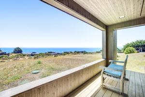 a rocking chair sitting on a porch looking out at the ocean at Ascona House in Sea Ranch