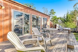 a deck with chairs and tables and windows at Cove House in Gualala