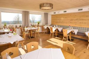 a restaurant with white tables and chairs and windows at Landhotel Sonne Neuhäusle in Sankt Märgen