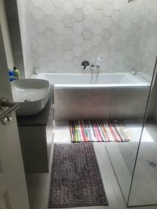 a bathroom with a tub and a sink and a rug at Crystal Self Catering 3 bedroom Villa in Swakopmund