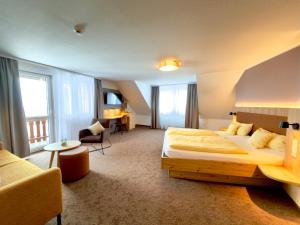 a hotel room with a large bed and a couch at Landhotel Sonne Neuhäusle in Sankt Märgen