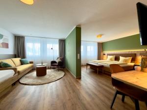 a hotel room with a bed and a couch at Landhotel Sonne Neuhäusle in Sankt Märgen