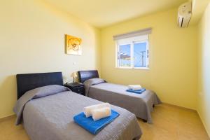 een kamer met 2 bedden en een raam bij Athoniki Villas in Kalathos