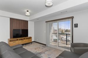 a living room with a couch and a flat screen tv at Lux Suites Extended Stay in Thunder Bay