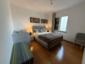 a bedroom with a bed and a chair in it at Tamariz Adventure - Sea View and Free Parking in Caniço