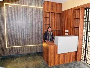 a woman is standing at a desk in a room at Sheetal Service Apartment in Mangalore