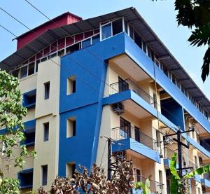 a blue and white building with a red roof at Sheetal Service Apartment in Mangalore
