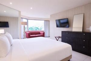 a bedroom with a large white bed and a television at Torarica Resort in Paramaribo