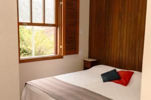 a bedroom with a white bed with a window at Casa Antunes in Diamantina