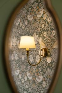a lamp on a wall with a floral wallpaper at House Arundel in Arundel
