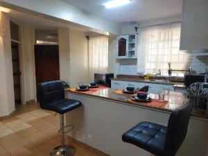 a kitchen with a counter and two chairs at a bar at Dobajo Homes2 in Kisumu