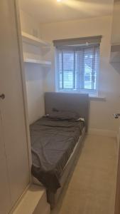 a small bed in a room with a window at Brooklyn House in Elmers End