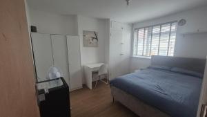a bedroom with a bed and a desk and a window at Brooklyn House in Elmers End