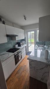 a kitchen with white cabinets and a wooden floor at Brooklyn House in Elmers End