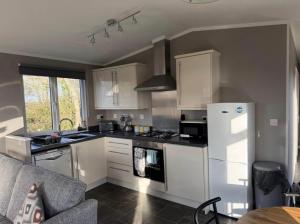 a kitchen with white cabinets and a white refrigerator at Two Bedroom Lodge in Gainsborough