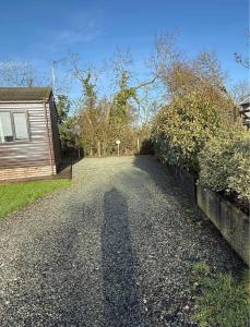 a road leading to a house with a long shadow at Two Bedroom Lodge in Gainsborough