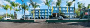 a parking lot in front of a building with palm trees at Brivali Hotel Centro in Caçador