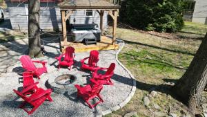 a group of red chairs and a gazebo at Spacious cabin w private river, hot tub & fire pit in Harpers Ferry
