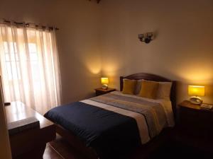 a bedroom with a bed with two lamps and a window at Casa Poço Azul in Achadinha