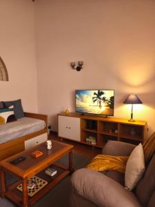 a living room with a couch and a flat screen tv at Casa Poço Azul in Achadinha