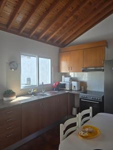 a kitchen with wooden cabinets and a table and a sink at Casa Poço Azul in Achadinha