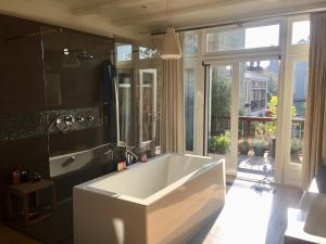 a large white tub in a bathroom with a window at Boutique Home in Maassluis +41 photos