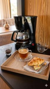 a tray with a cup of coffee and a croissant at Chalés da colina em Victor Graeff in Cochinho