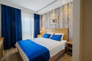 a bedroom with a large bed with blue pillows at Minerva Hotel Kızkalesi in Kizkalesi