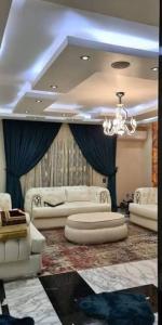 a living room with white furniture and a chandelier at دوبلكس شرق in Madīnat ash Shurūq +3 photos