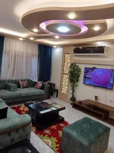 a living room with a couch and a flat screen tv at دوبلكس شرق in Madīnat ash Shurūq
