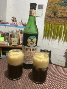 two glasses of beer sitting on a table with a bottle at Luna Munay Hostel in Curití
