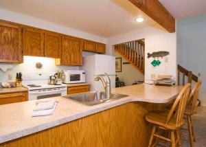 a kitchen with a sink and a counter with chairs at 10 Quelah Condo in Sunriver