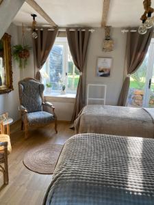 a bedroom with two beds and a chair and a window at Gîte la belle etoile proche de Granville in Ver