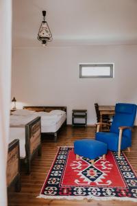 a bedroom with two beds and a blue chair and a rug at Green Sheep Boutique Hotel in Kazbegi