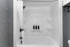 a bathroom with a shower with three bottles of soap at Lux Suites Extended Stay in Thunder Bay +25 photos