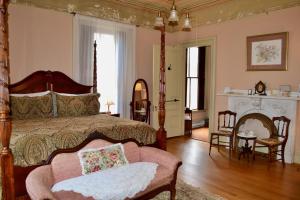 a bedroom with a bed and a chair and a fireplace at Proctor Mansion Inn in Wrentham